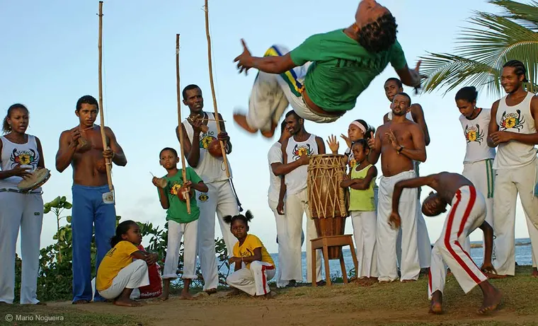 Roda de capoeira na praia em Itacaré, com berimbau, atabaque e dançarinos